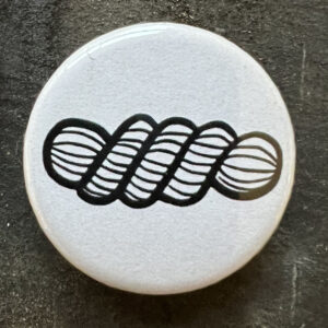 Pin badge with the line drawing of a skein of yarn. Black lines, white background.