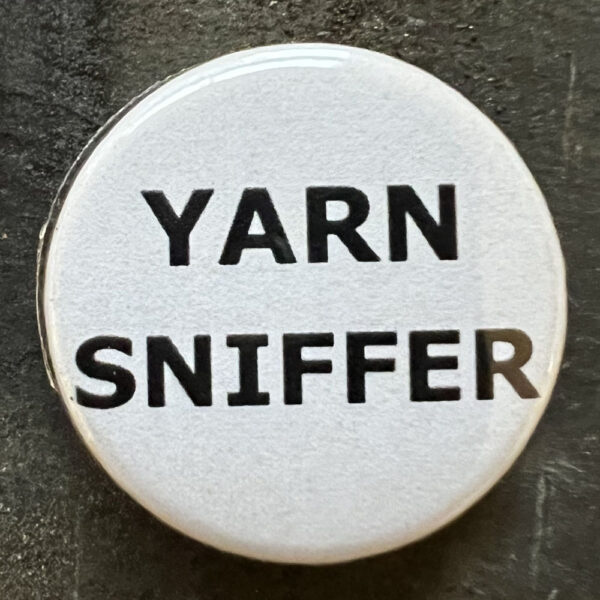 Pin badge with the words YARN SNIFFER . Black text, white background.